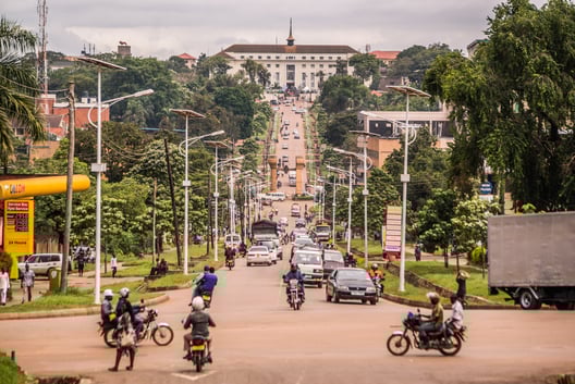 A landscape picture of Kampala, Uganda, looking up to the parlament. Busy street with cars and motorbikes.